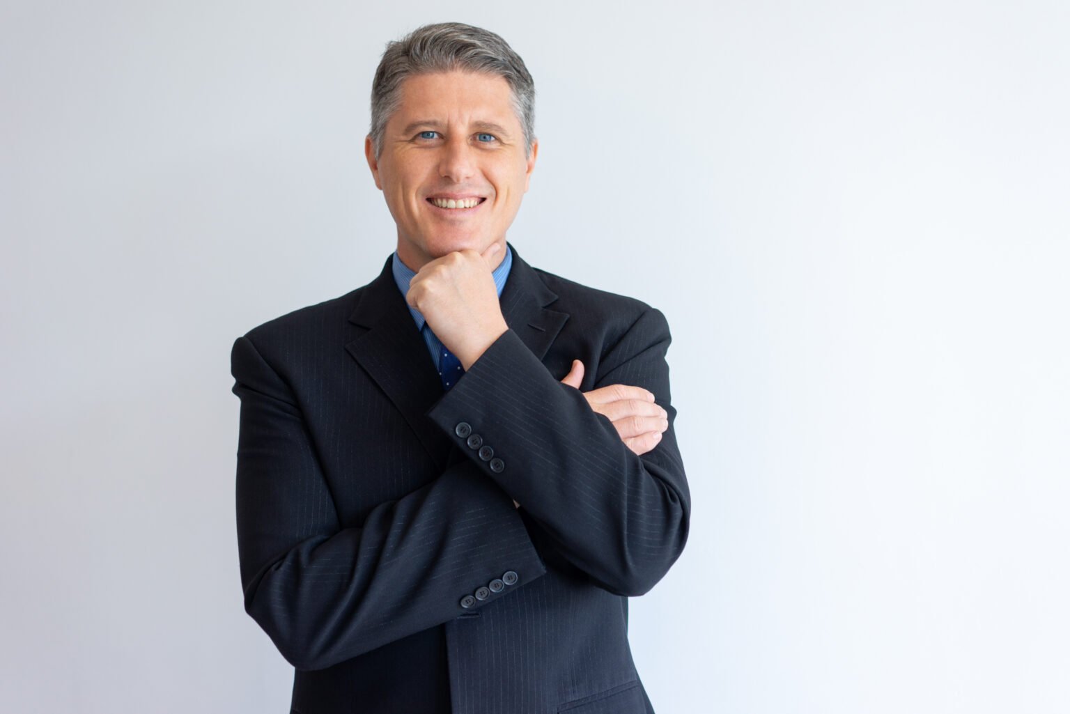 Portrait of positive confident businessman. Middle aged Caucasian man in jacket and tie touching chin and smiling at camera. Successful business leader concept